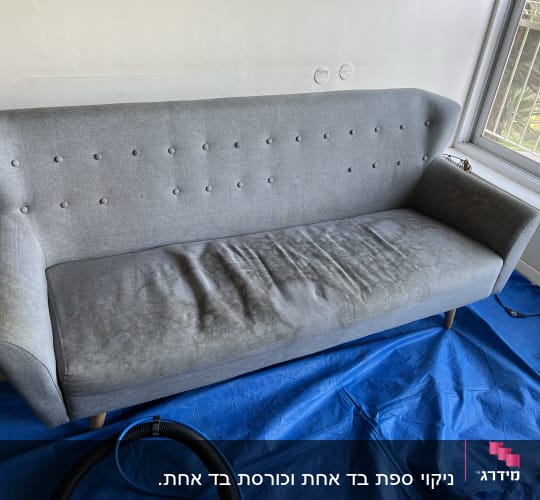 ספה אפורה עם כתמים על יריעת פלסטיק כחולה